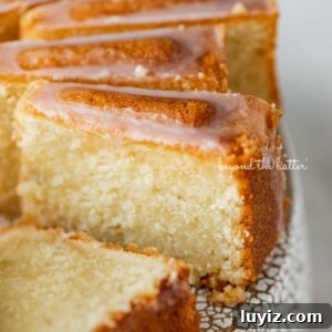 Lemon Cream Cheese Pound Cake Recipe with Zesty Glaze 14 Sliced lemon cream cheese pound cake with a lemon glaze on a cake stand.