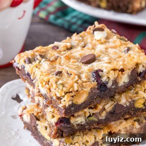 A stack of 3 christmas magic cookie bars with a gingersnap crust and coconut topping.