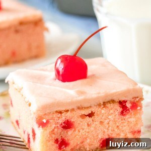 A slice of maraschino cherry cake with cherry frosting and a cherry on top