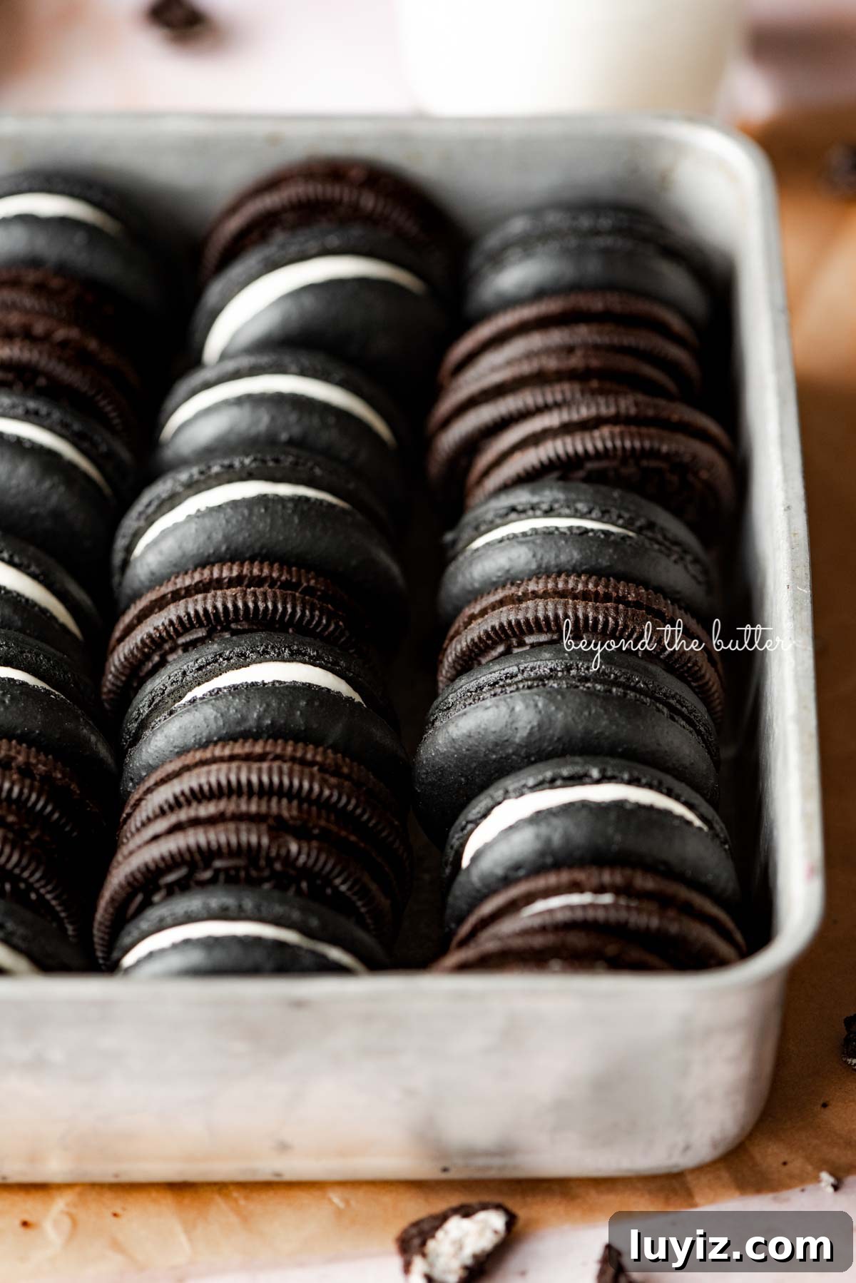 Oreo Cookie Macarons: Step-by-Step Recipe for Perfect Bites 5 Oreo macarons and oreo cookies in a vintage baking tin on parchment paper