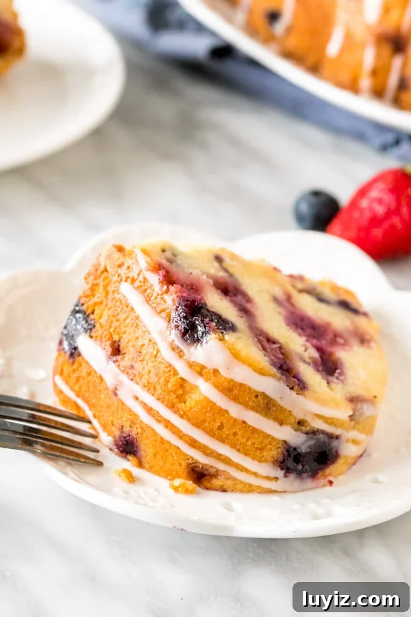 Moist Mixed Berry Bundt Cake Recipe with Lemon Glaze 4 Slice of bundt cake with a drizzle of glaze on its side.