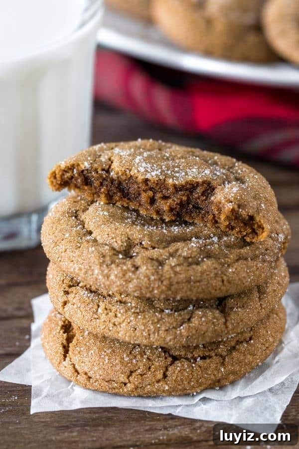 Soft Chewy Ginger Molasses Cookies Recipe 5 A stack of thick ginger molasses cookies with the top cookie broken in half.