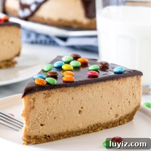 Slice of monster cookie cheesecake with a glass of milk. 2nd piece of cheesecake and entire cheesecake in the background.