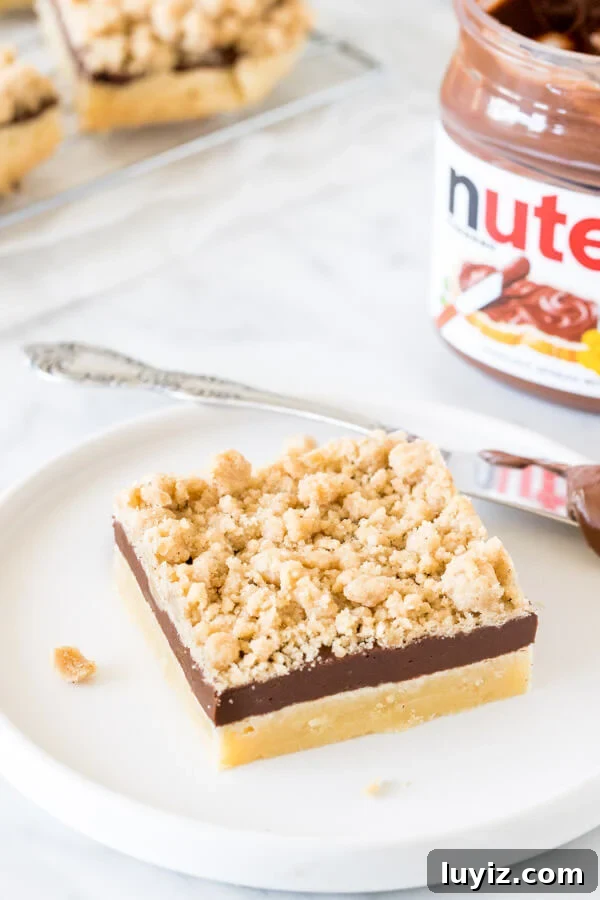 Chewy Nutella Crumb Bars with Chocolate Swirls 5 Nutella shortbread bar on a plate with a jar of Nutella
