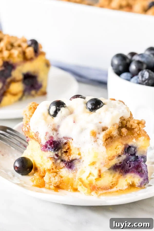 Blueberry French Toast Casserole Recipe for Brunch and Holidays 4 Slice of french toast bake with bite taken out of it. Whipped cream on top melting down the sides.