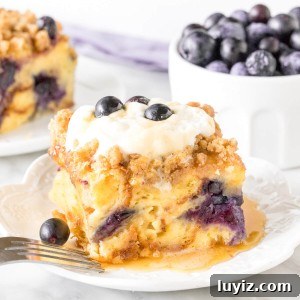 Slice of blueberry french toast casserole with whipped cream on top.