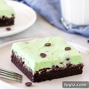 Brownie topped with mint chip frosting on a plate with a glass of milk.