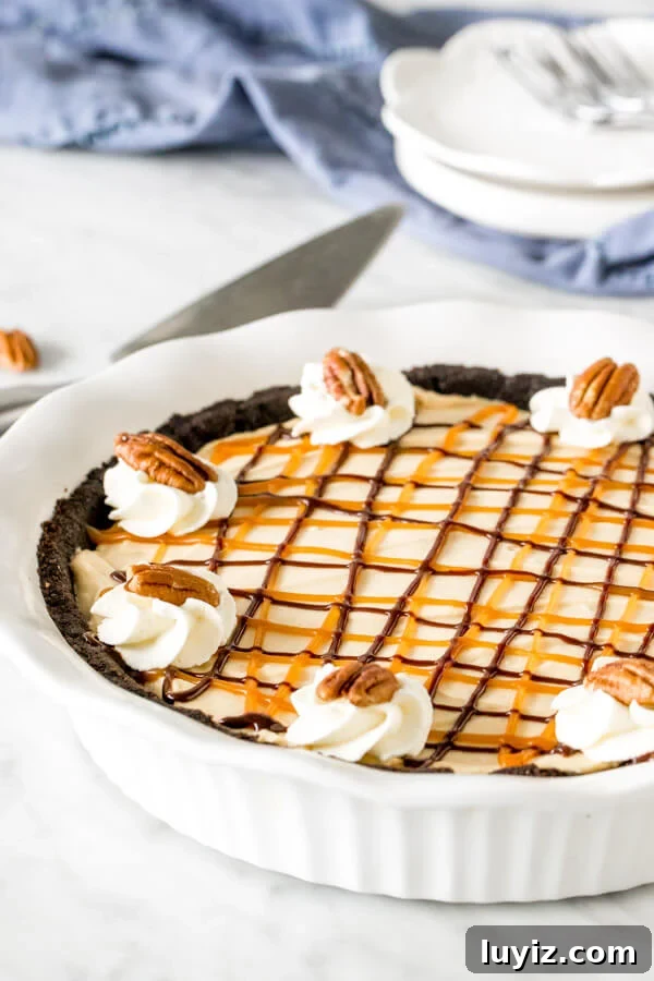 Decadent Turtle Pie Recipe with Pecan-Caramel Crunch 3 Turtle pie in white pie plate with whipped cream, caramel & chocolate on top.