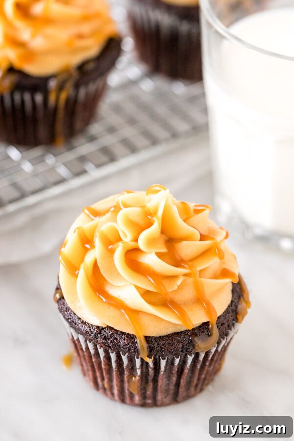Silky Caramel Frosting Recipe for Cakes and Cupcakes 4 Cupcake topped with caramel buttercream and drizzled with salted caramel drizzled on top with a glass of milk.