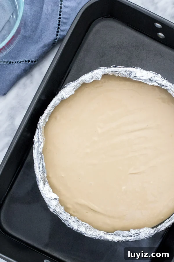 Decadent Coffee Cheesecake Recipe for Coffee Lovers 4 Unbaked coffee cheesecake in water bath with the pan wrapped in aluminum foil.