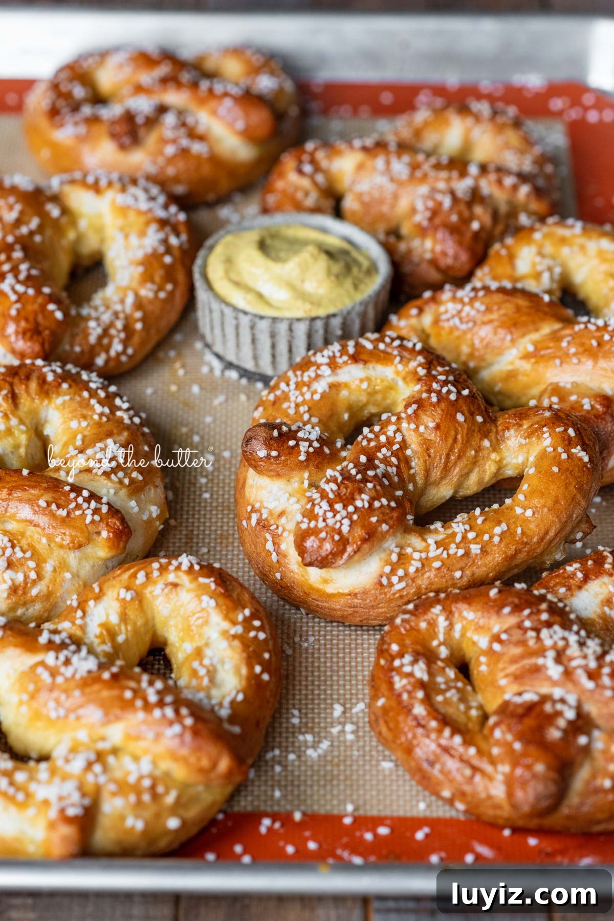 How to Make Soft Homemade Pretzels Step-by-Step 4 Homemade soft pretzels on a silicone lined baking sheet ready for dipping into spicy mustard | © Beyond the Butter®