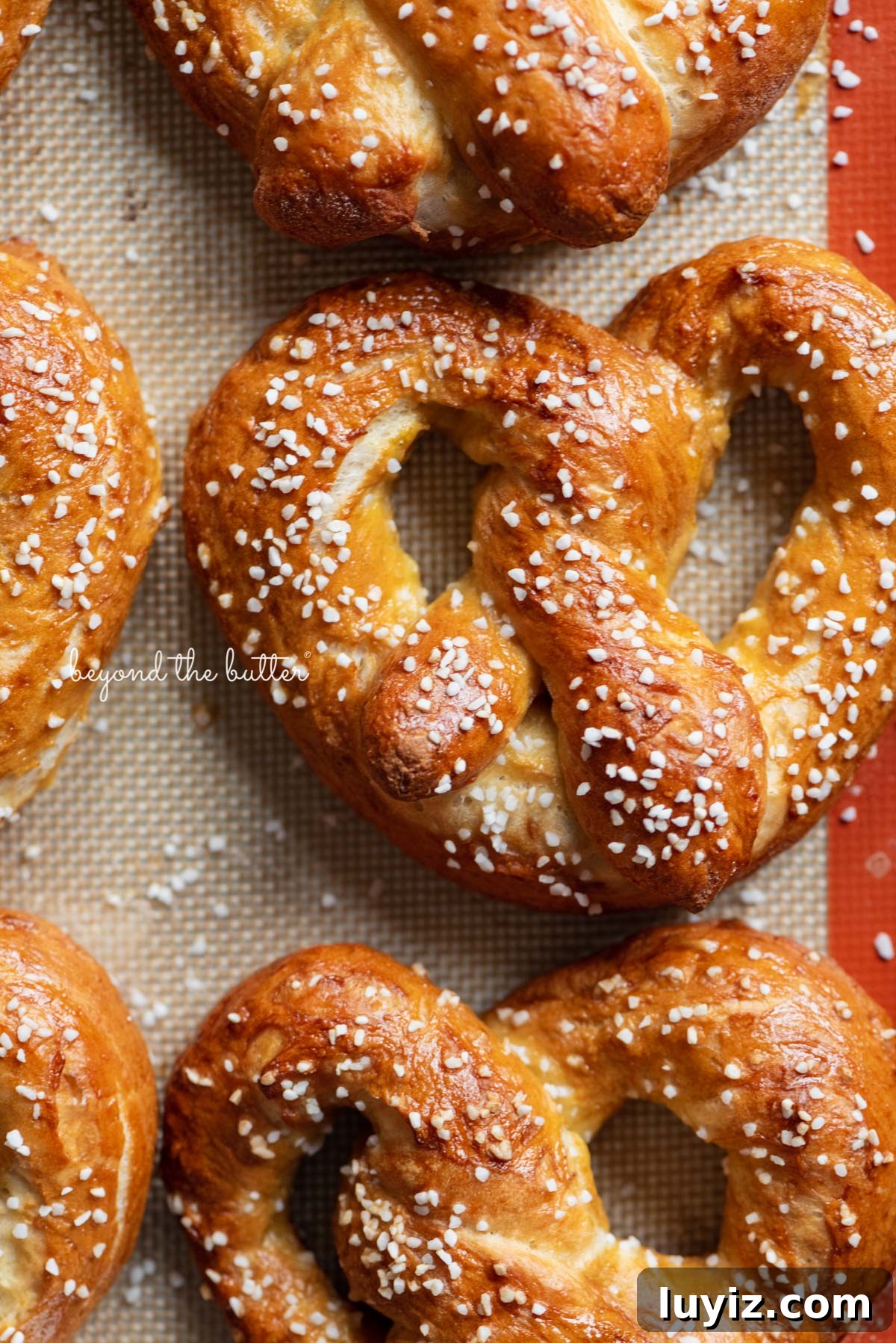 How to Make Soft Homemade Pretzels Step-by-Step 9 Homemade soft pretzels on a silicone baking mat and baking sheet | © Beyond the Butter®