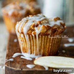 Apple Cinnamon Streusel Muffins Recipe with Crunchy Topping 10 Warm apple cinnamon streusel muffins on a wood cutting board with slices of apples and vanilla glaze.
