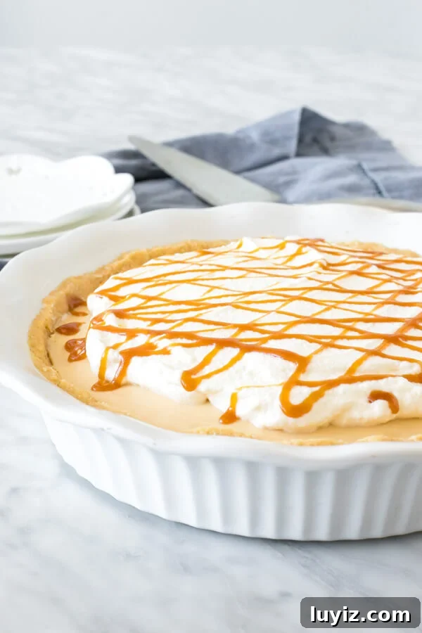 Decadent Caramel Cream Pie Recipe: Silky, No-Bake Dessert 3 No-Bake caramel cream pie in a white pie plate topped with whipped cream and a drizzle of caramel sauce.