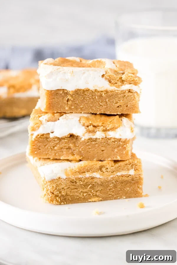 Fluffernutter Bars Recipe: Classic Peanut Butter & Marshmallow Squares 5 Stack of 3 marshmallow peanut butter bars on a plate with a glass of milk.