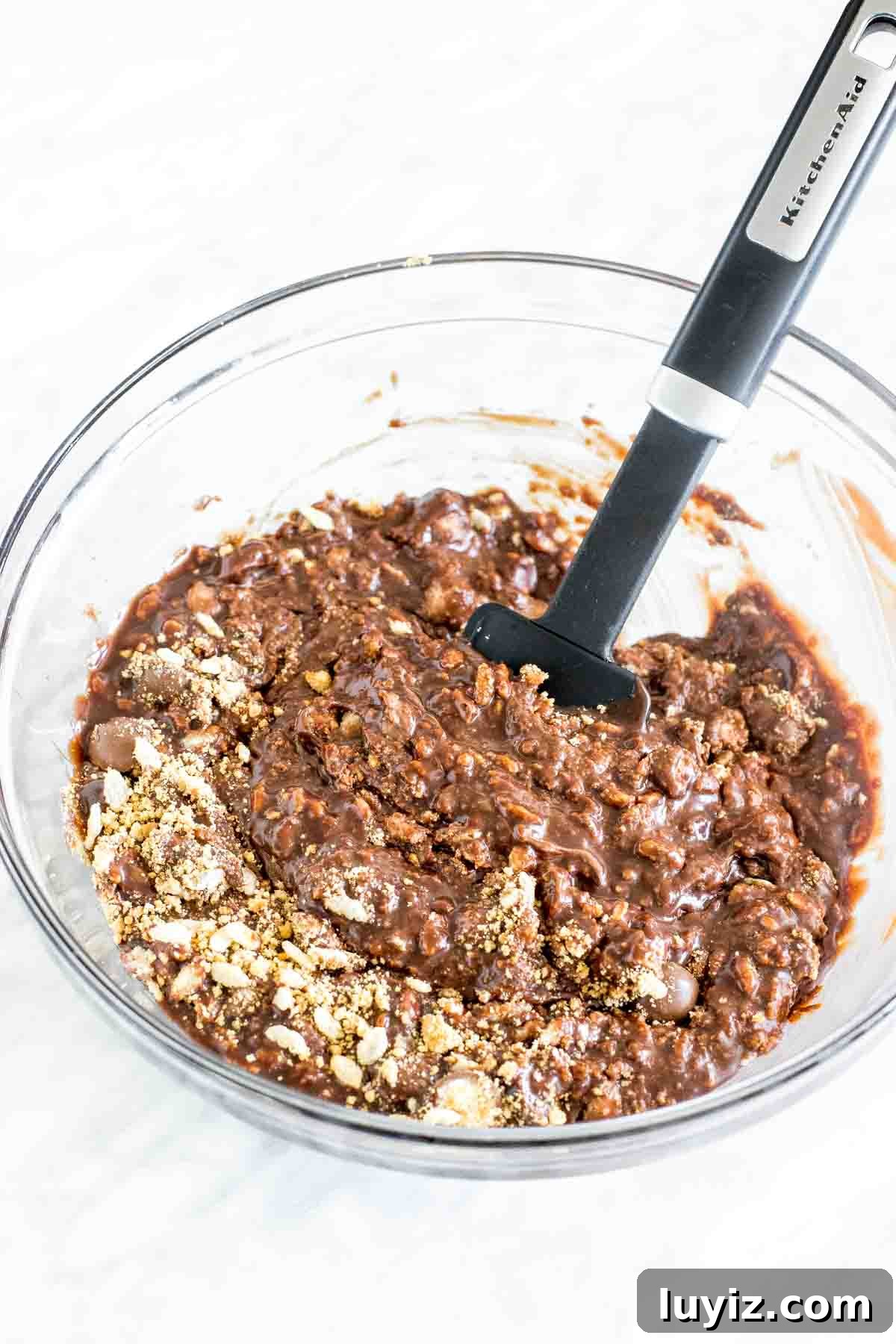 No-Bake Malteser Slice Recipe — Crunchy Chocolate Slice 3 Chocolate fudge poured over cereal, crushed biscuits, and candies in a bowl.