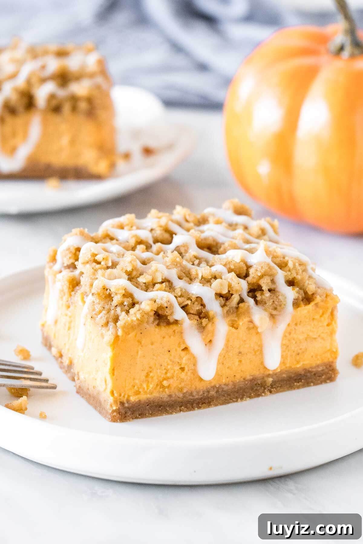 Pumpkin Streusel Bars Recipe — Perfect Fall Dessert Bars 45 Slice of pumpkin streusel bars on a plate with a second piece in the background.