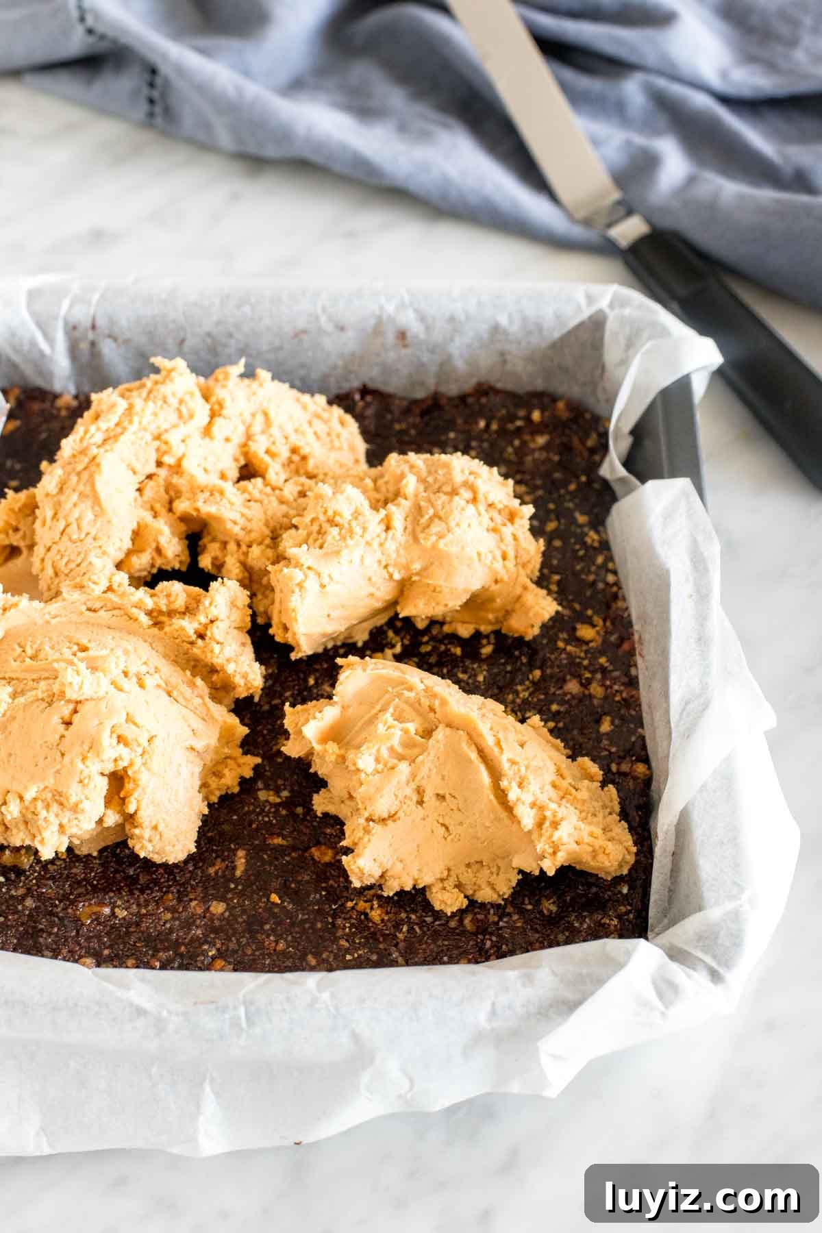 Peanut Butter Nanaimo Bars Recipe: No-Bake Cheesecake-Style Squares 4 Nanaimo bar base layer with peanut butter filling spooned on top in an 8x8 inch pan.
