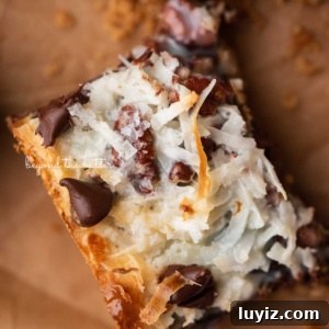 7-Layer Magic Cookie Bars Recipe (Classic Dessert Bars) 14 Magic cookie bar on brown parchment paper.