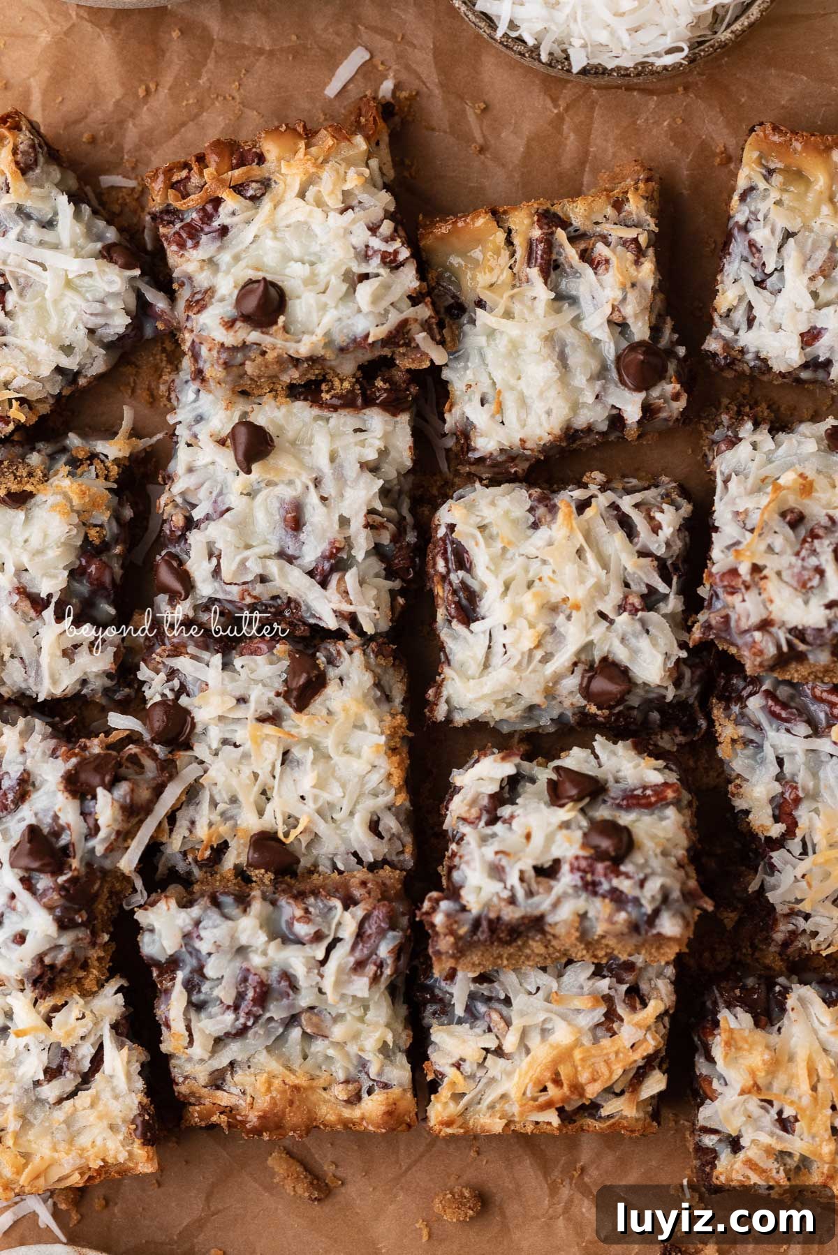 7-Layer Magic Cookie Bars Recipe (Classic Dessert Bars) 3 7 layer magic cookie bars on brown parchment paper | © Beyond the Butter®