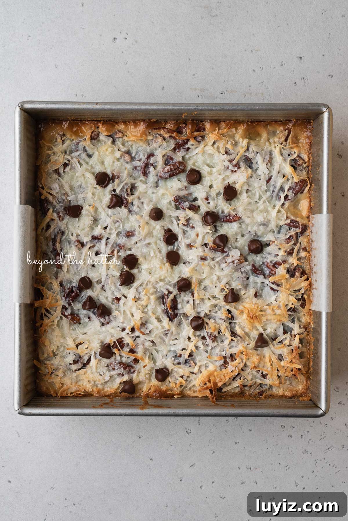 7-Layer Magic Cookie Bars Recipe (Classic Dessert Bars) 4 Just baked 7 layer magic cookie bars in 8 inch baking pan | © Beyond the Butter®