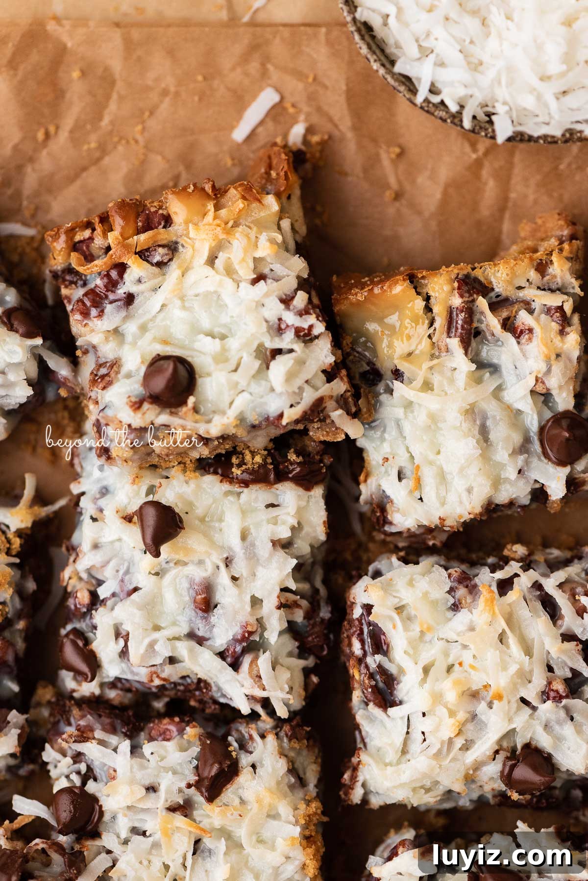 7-Layer Magic Cookie Bars Recipe (Classic Dessert Bars) 5 7 layer magic cookie bars on brown parchment paper | © Beyond the Butter®