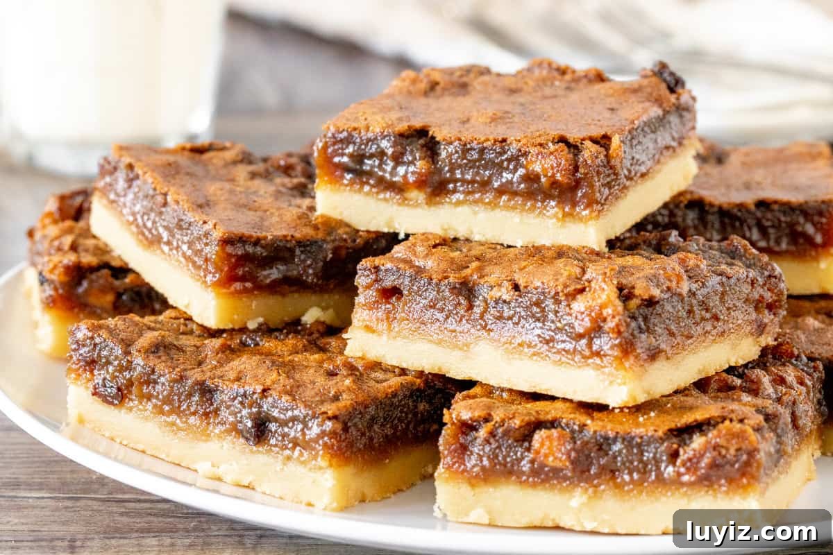 Classic Butter Tart Squares Recipe — Gooey Canadian Dessert 5 Plate of butter tart squares, stacked on top of each other.