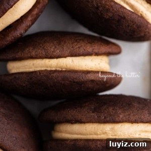 Chocolate Peanut Butter Whoopie Pies Recipe — Soft, Gooey Sandwich Cookies 8 Chocolate peanut butter whoopie pies on a parchment lined baking pan.
