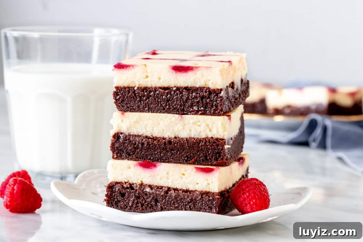 Raspberry Swirl Cheesecake Brownies Recipe 5 Stack of layered cream cheese brownies with a raspberry swirl on a plate.