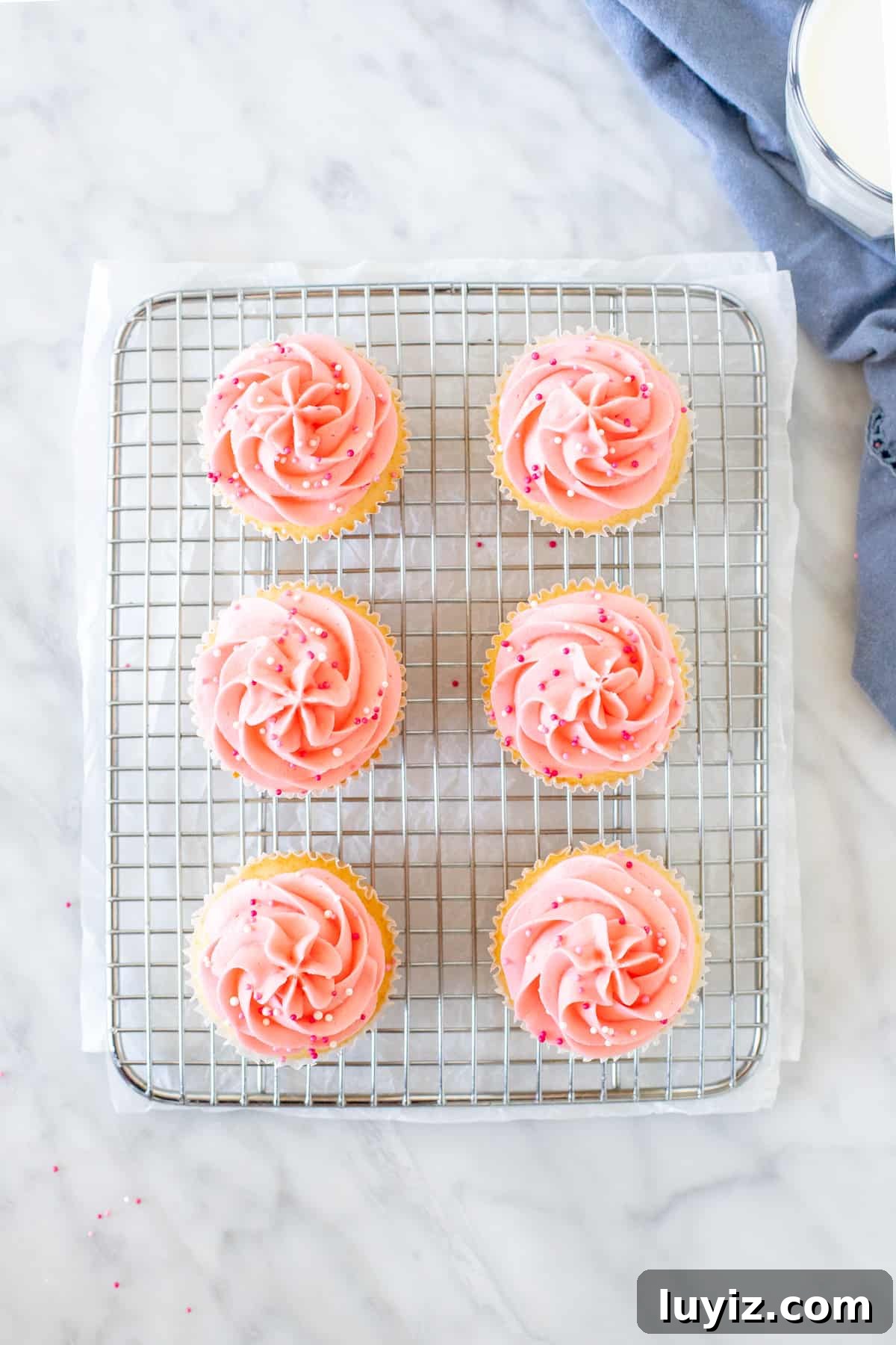 Perfect Small-Batch Vanilla Cupcakes Recipe for 12 Cupcakes 3 6 pink cupcakes on a cooling rack.
