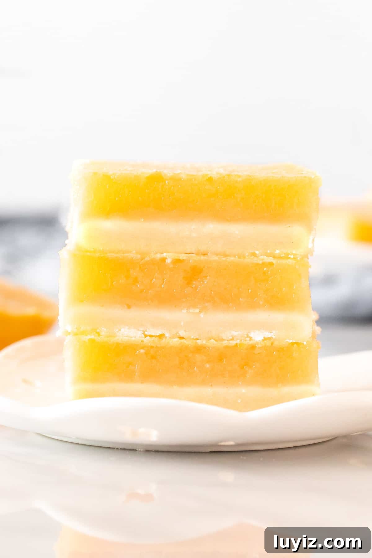 Tangy Lemon Bars Recipe with Buttery Shortbread Crust 2 Stack of 3 lemon bars on a plate.