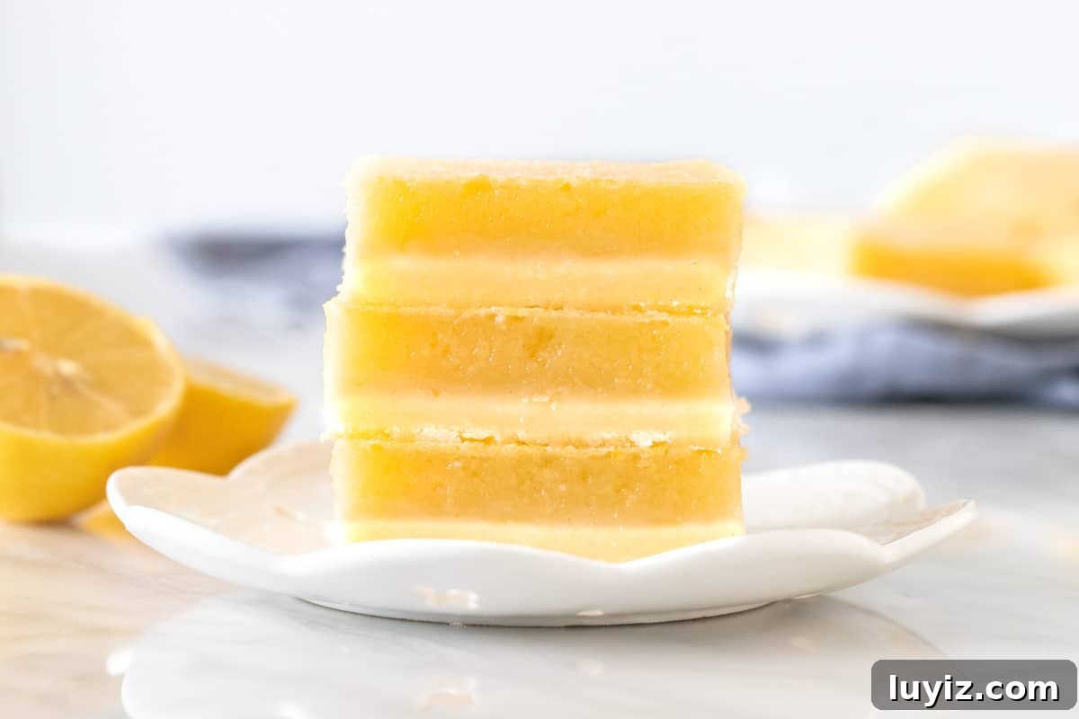 Tangy Lemon Bars Recipe with Buttery Shortbread Crust 7 3 lemon bars stacked on a plate.