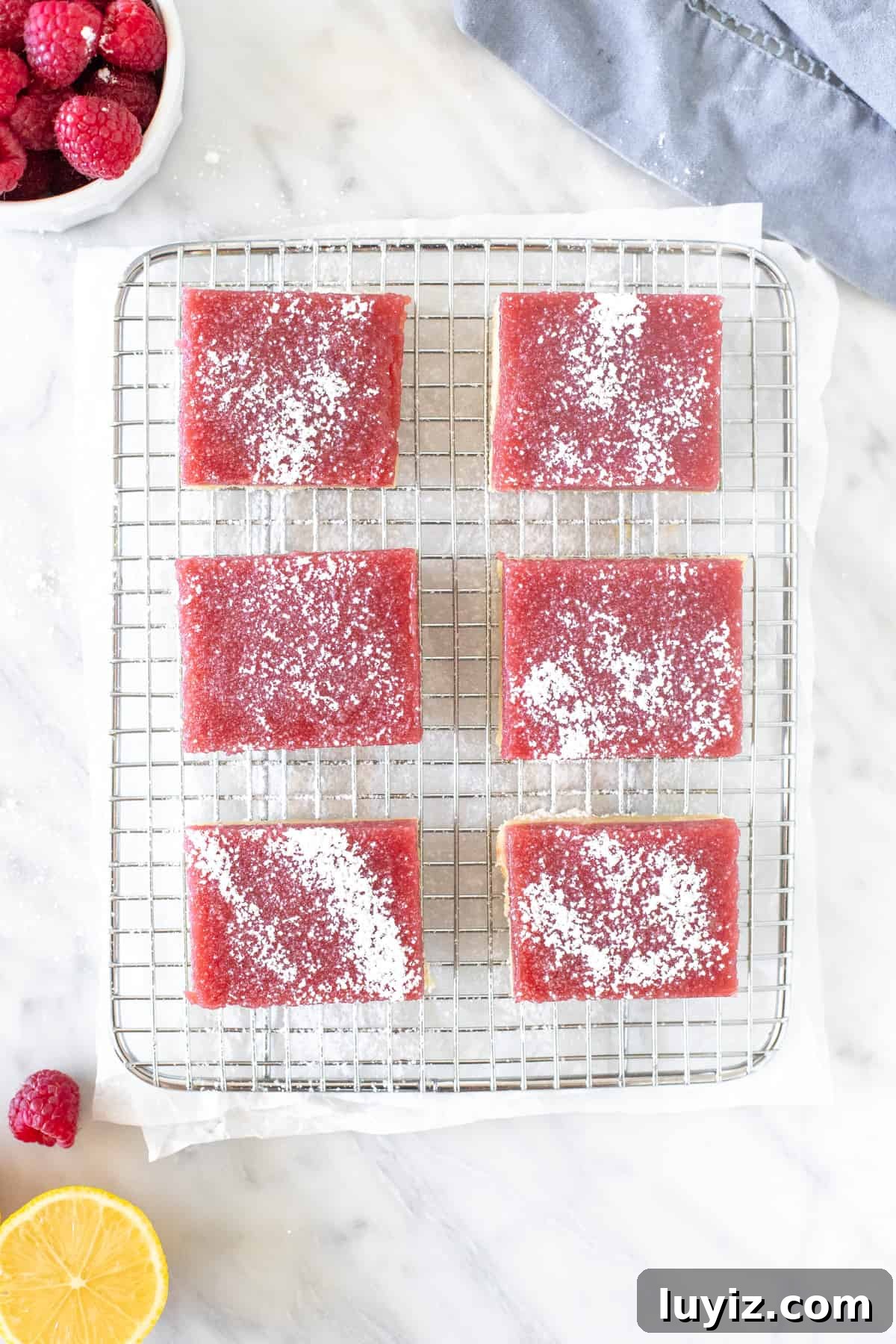 Zesty Lemon Raspberry Dessert Bars — Bright Tart Bar Recipe 3 6 raspberry lemonade bars sprinkled with powdered sugar on a cooling rack.