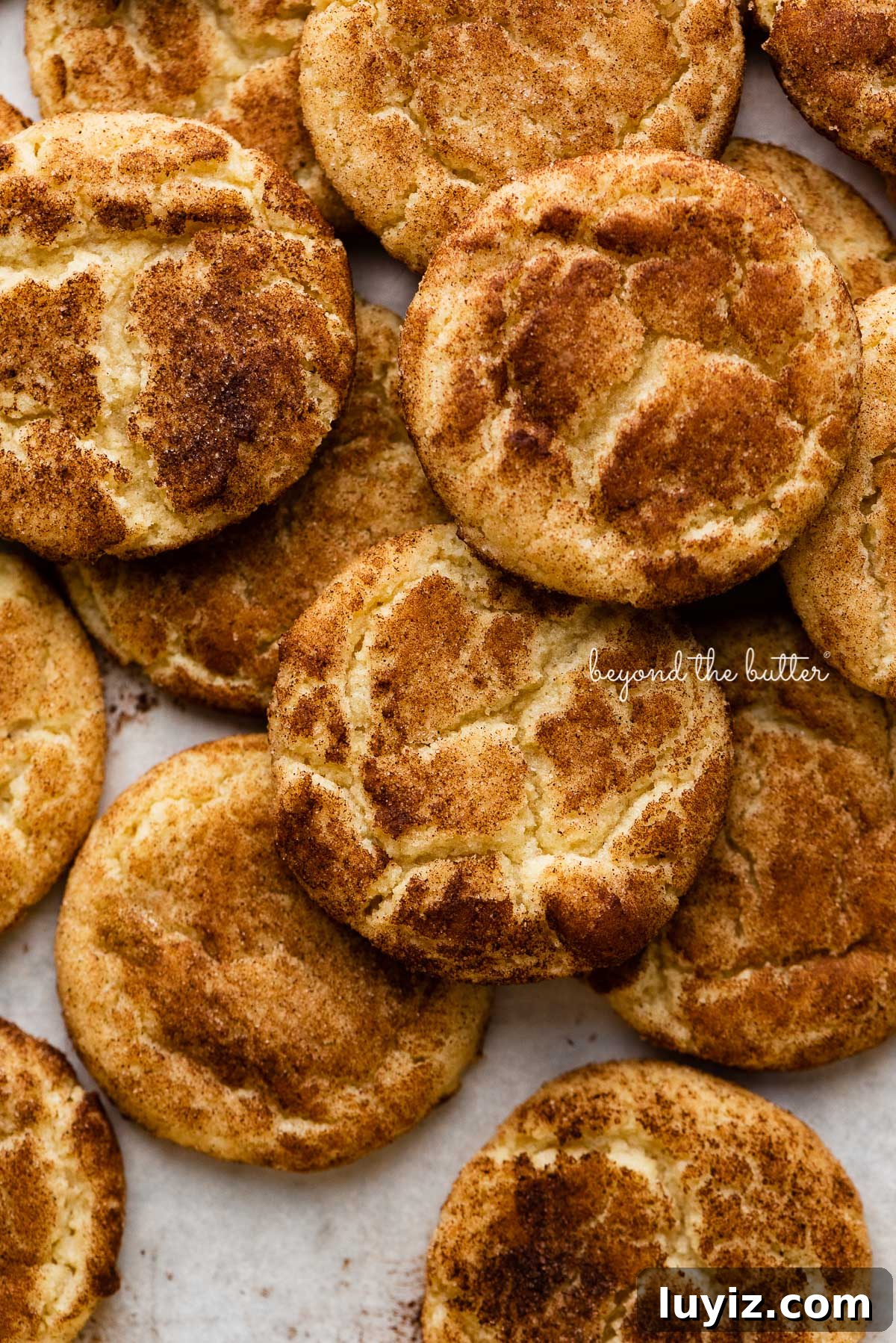 Classic Snickerdoodle Cookie Recipe: Soft Cinnamon Sugar Cookies 5 Piled snickerdoodle cookies on a parchment paper lined baking sheet | © Beyond the Butter®