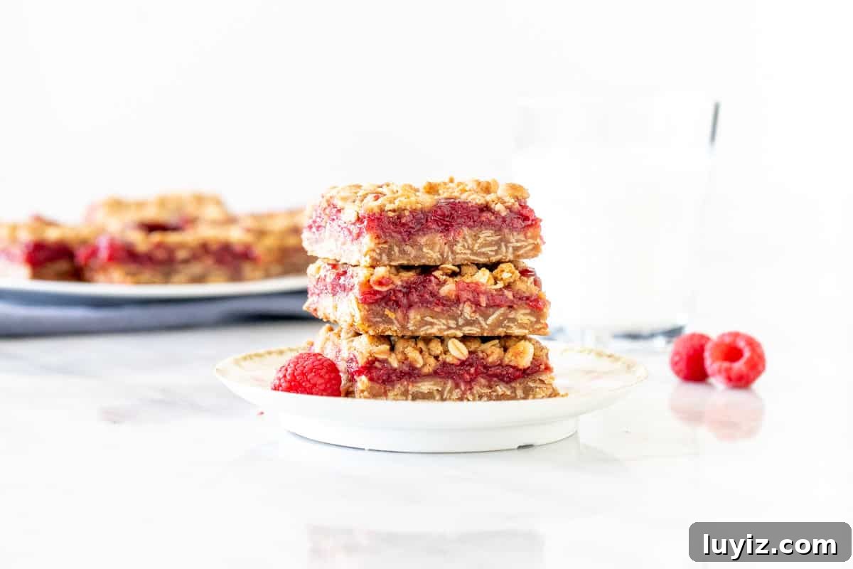 Chewy Raspberry Jam Bars with Oat Crust 6 Raspberry bars stacked on a plate.