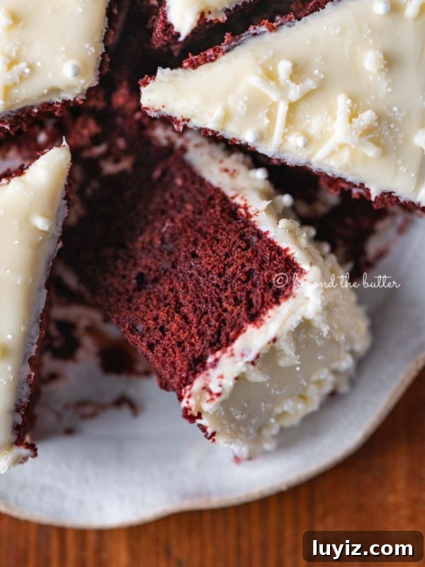 Holiday Jamboree Cookie Recipes for Festive Baking 7 Sliced red velvet cake with cream cheese frosting on a scalloped edge dessert plate with red plaid background.