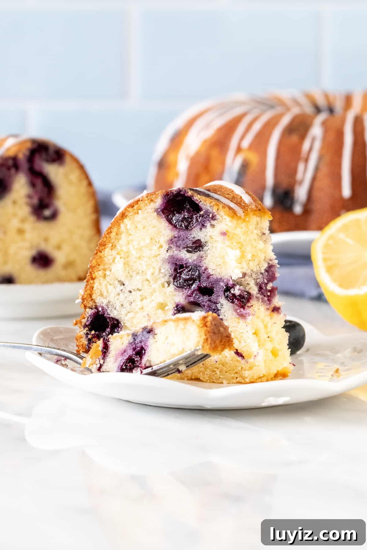 Lemon Blueberry Bundt Cake Recipe with Zesty Glaze 4 Slice of lemon blueberry bundt cake, with bite taken out.