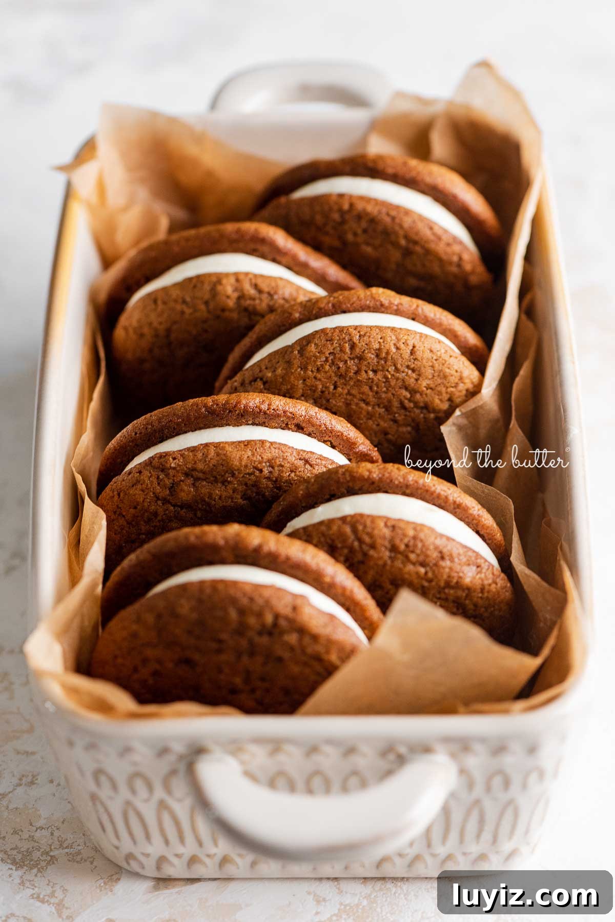 Gingerbread Whoopie Pies Recipe: Soft Molasses Sandwich Cookies 3 Natural parchment paper lined ceramic baking pan with homemade gingerbread whoopie pies | © Beyond the Butter®