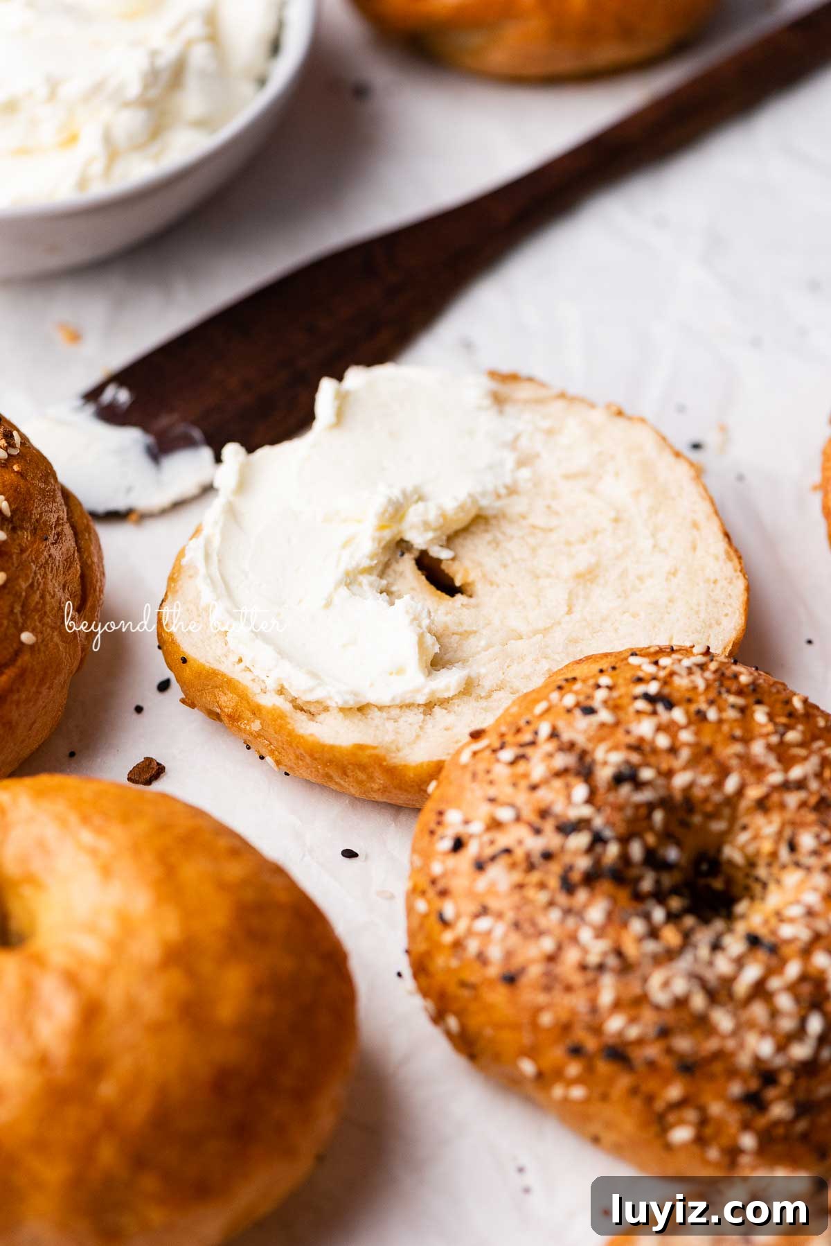 Homemade Bagel Recipe: How to Make Soft, Chewy Bagels at Home 3 Easy homemade bagel sliced with cream cheese partially spread over the top | © Beyond the Butter®
