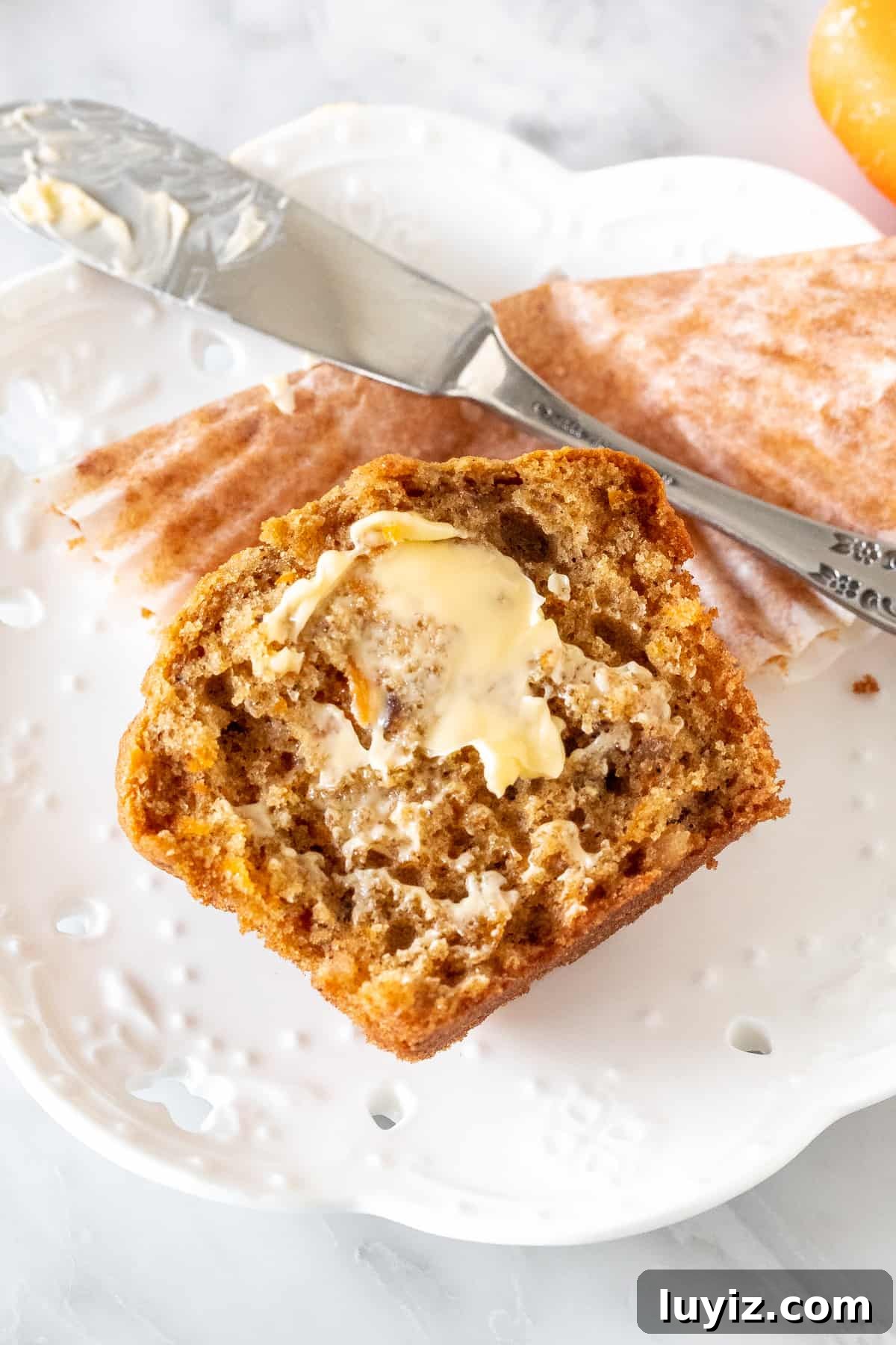 Moist Carrot Cake Muffins with Cream Cheese Frosting 5 Half a carrot cake muffin with butter on it.