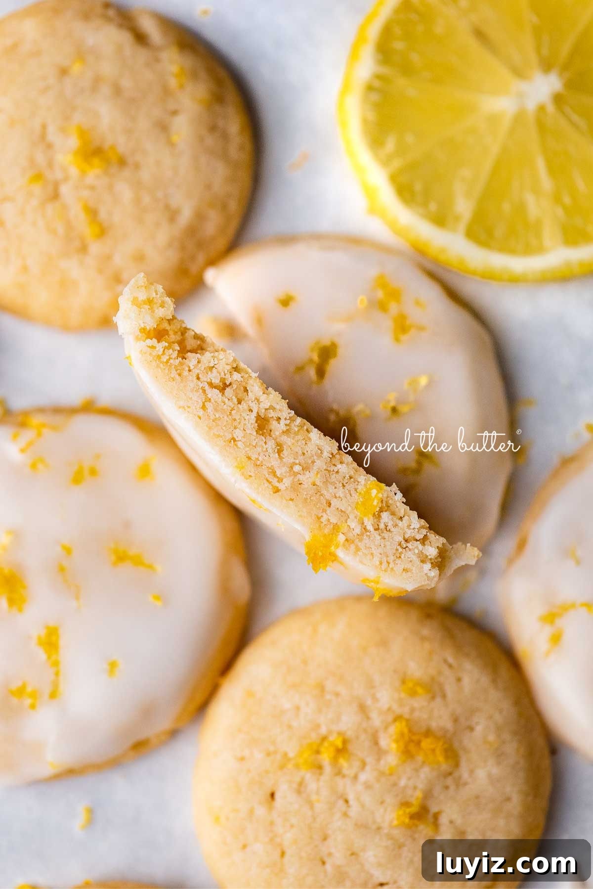 Zesty Lemon Shortbread Cookies: Crispy, Buttery Citrus Treats 4 Lemon shortbread cookies with center cookie cut in half with sliced lemon on white background.