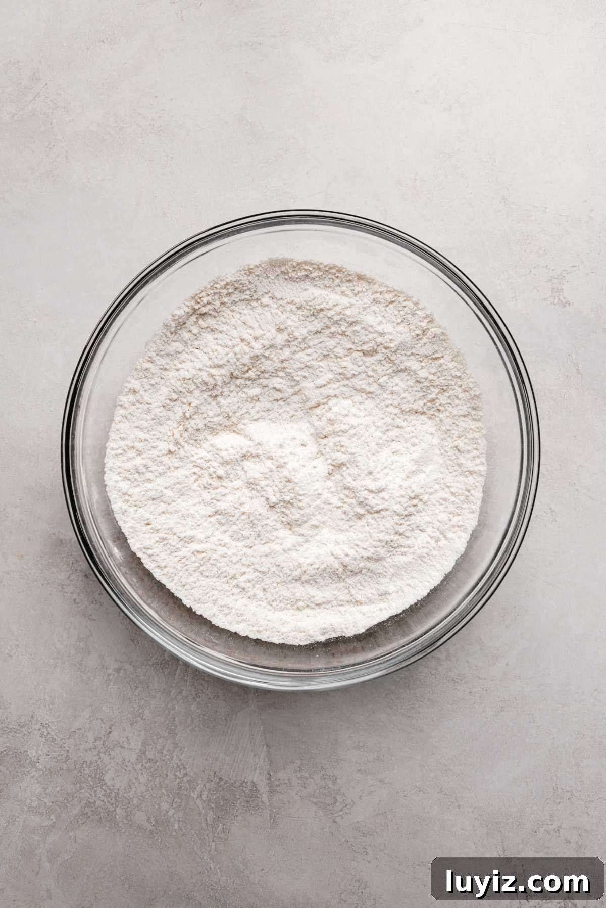 Zesty Lemon Shortbread Cookies: Crispy, Buttery Citrus Treats 6 Whisked all purpose flour, baking powder, and salt in a large glass mixing bowl on a grey marbled background.