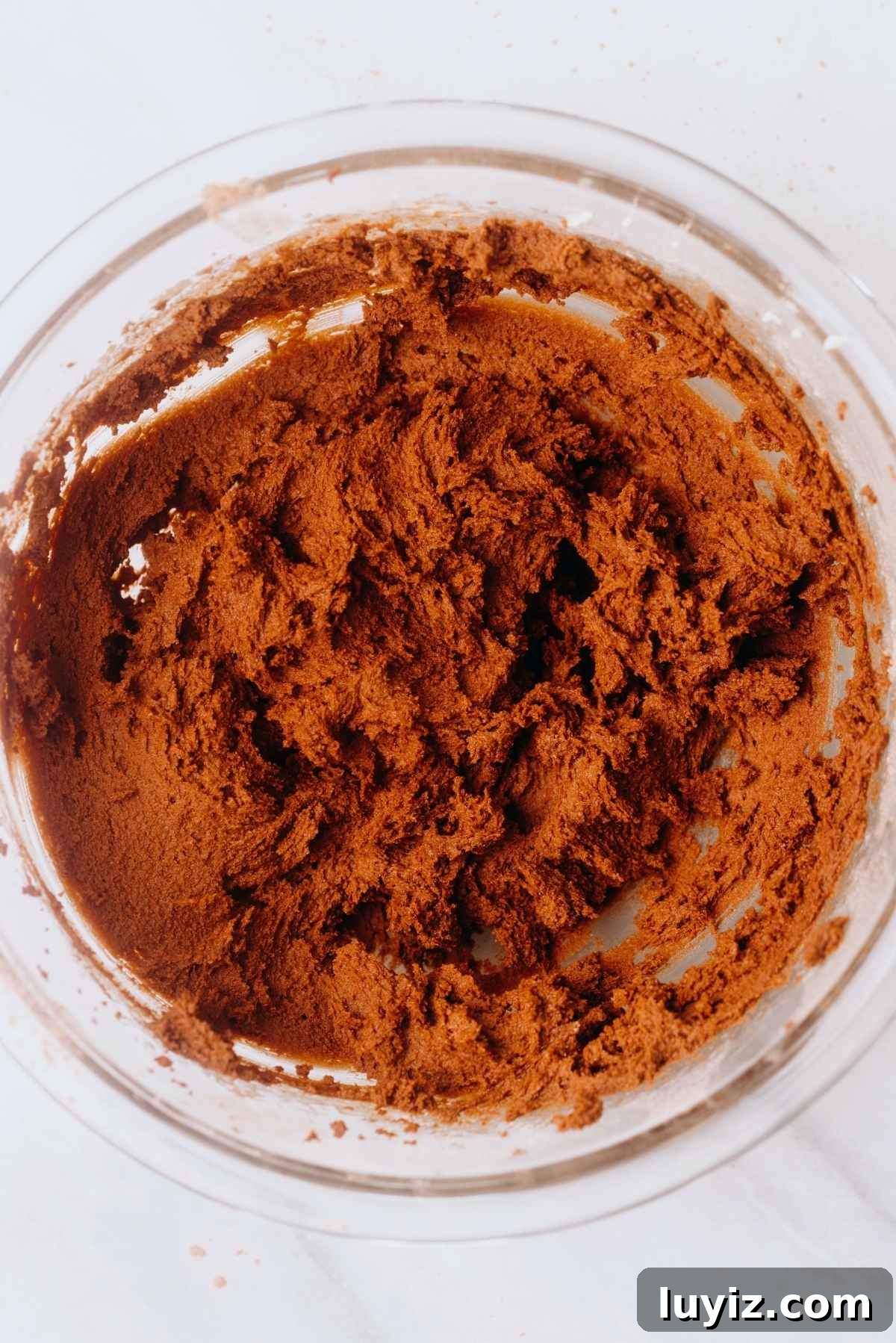 Homemade Thin Mints Recipe: Crisp Chocolate Mint Cookies 7 Dry ingredients blended together with wet ingredients to make homemade thin mint cookie dough in a large glass mixing bowl on a white marbled background.