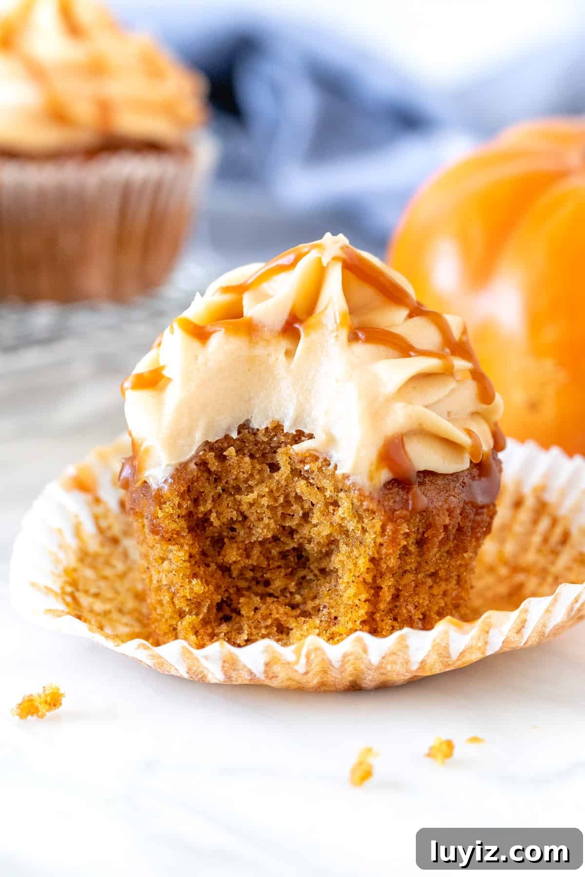 Pumpkin Cupcakes with Salted Caramel Cream Cheese Frosting 4 Pumpkin caramel cupcake with a bite taken out of it.
