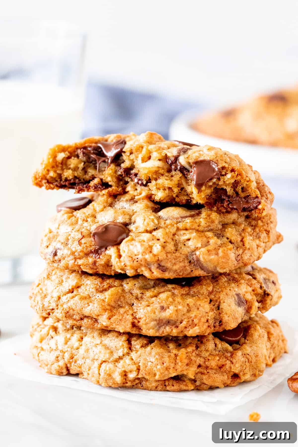 Chewy Cowboy Cookie Recipe with Oats, Chocolate & Pecans 5 Stack of oatmeal coconut chocolate chip cookies, with the top cookie broken in half