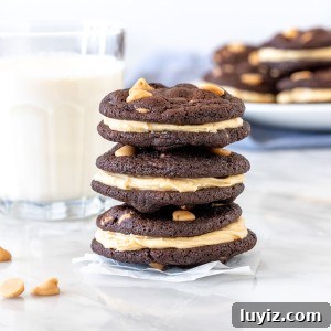 3 chocolate cookies with peanut butter chips and peanut butter frosting stacked on top of each other.