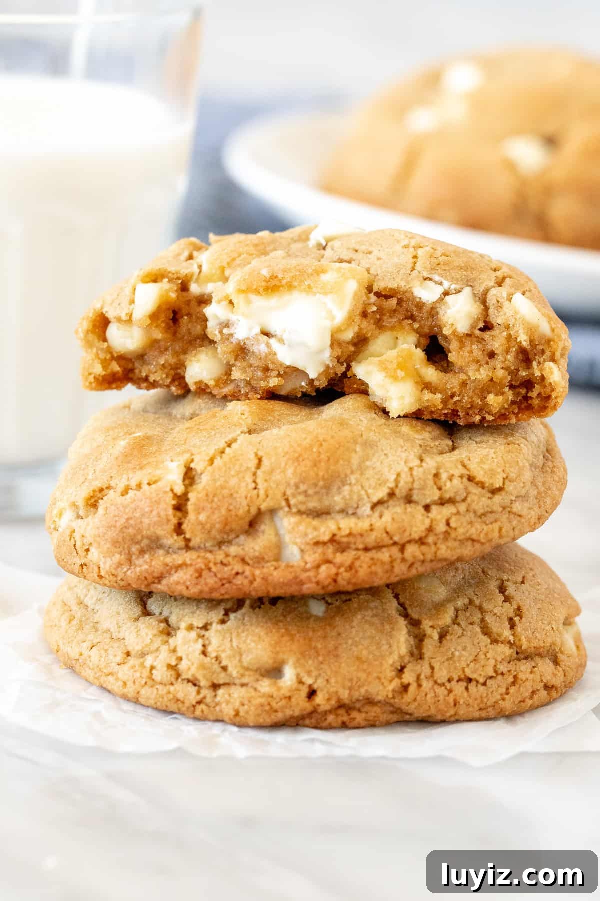Bakery-Style White Chocolate Macadamia Nut Cookies 2 Stack of bakery-style white chocolate macadamia cookies with top cookie broken in half.