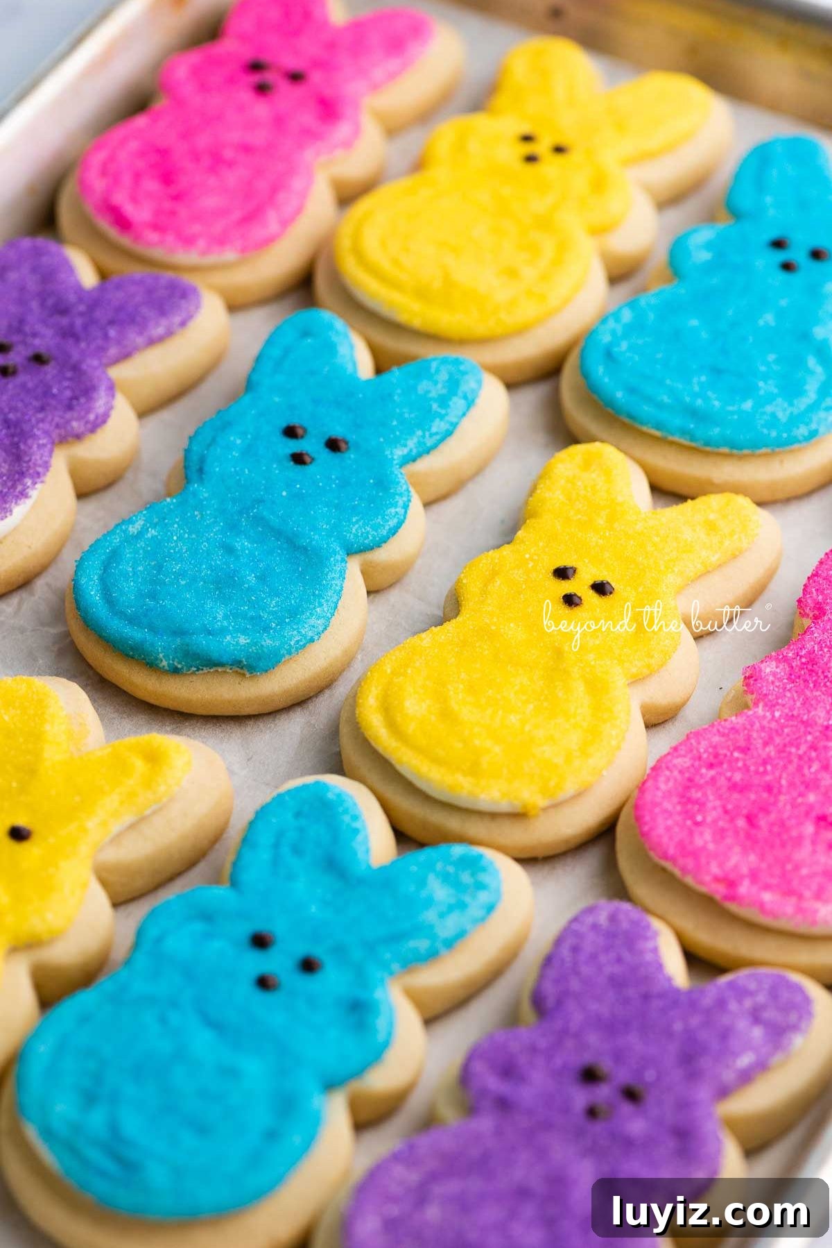 Easter Bunny Cut-Out Sugar Cookie Recipe 10 Easter bunny cut out sugar cookies on a parchment paper lined baking sheet.