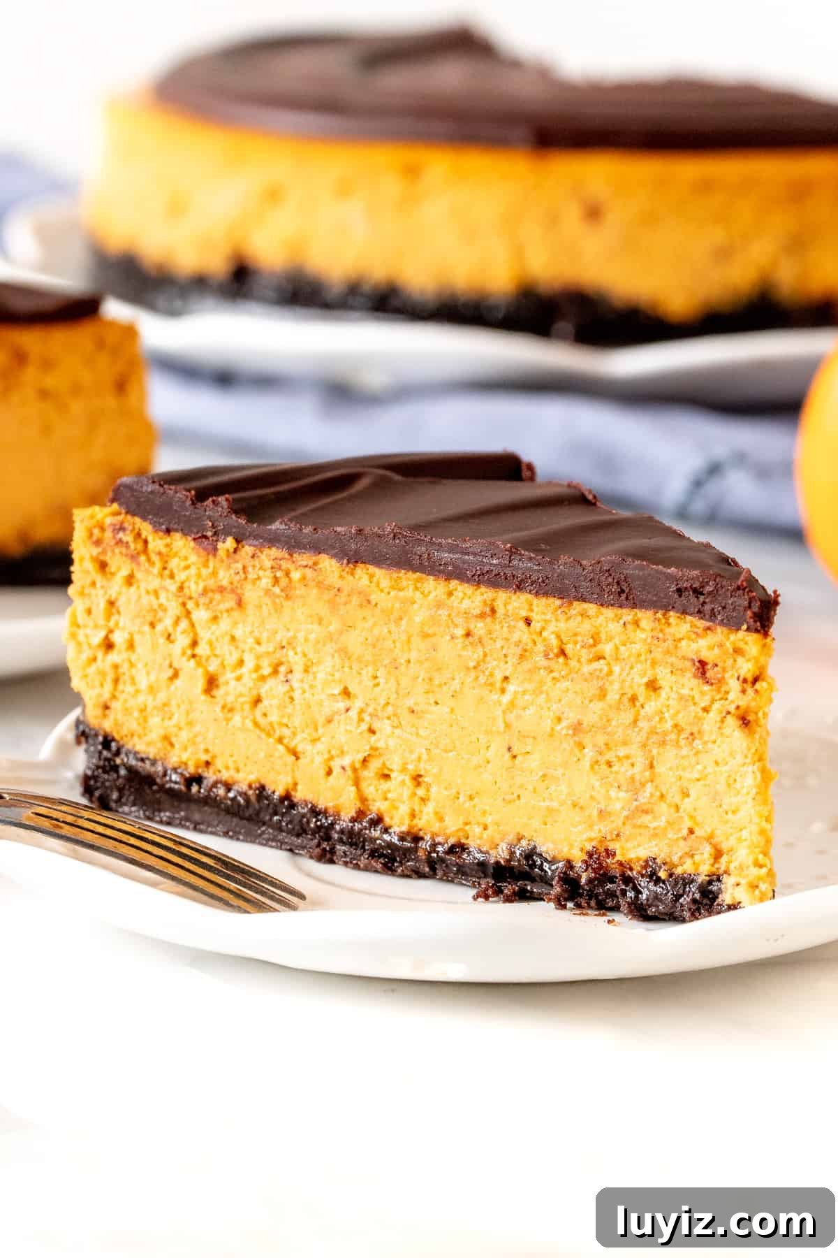 Pumpkin Chocolate Cheesecake Recipe: Decadent Fall Dessert 3 Slice of pumpkin cheesecake with chocolate ganache on top