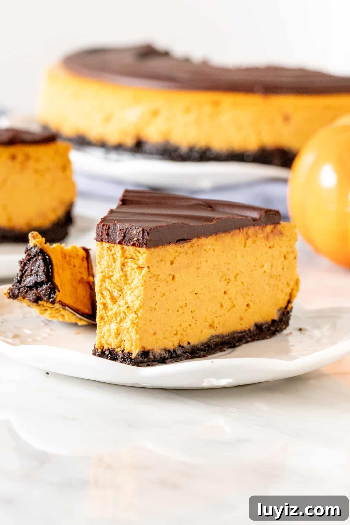 Pumpkin Chocolate Cheesecake Recipe: Decadent Fall Dessert 4 Piece of pumpkin chocolate cheesecake with an Oreo crust and a bite taken out.